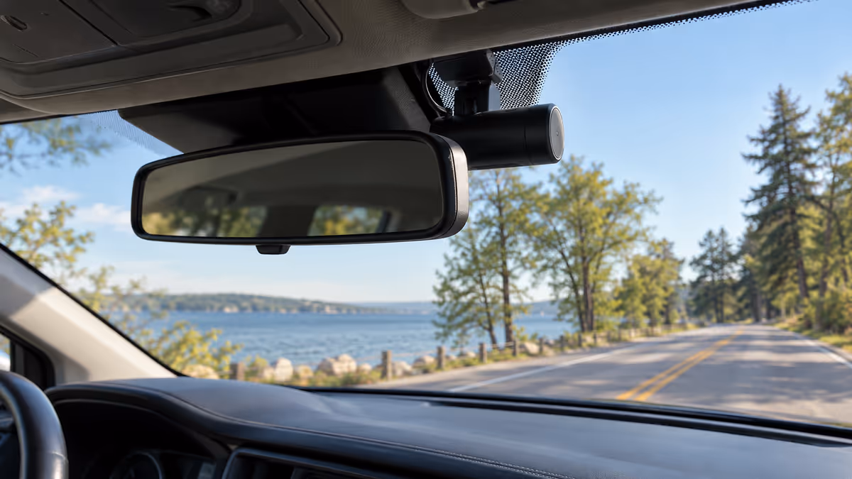 A camera sits discreetly beside a car rearview mirror.